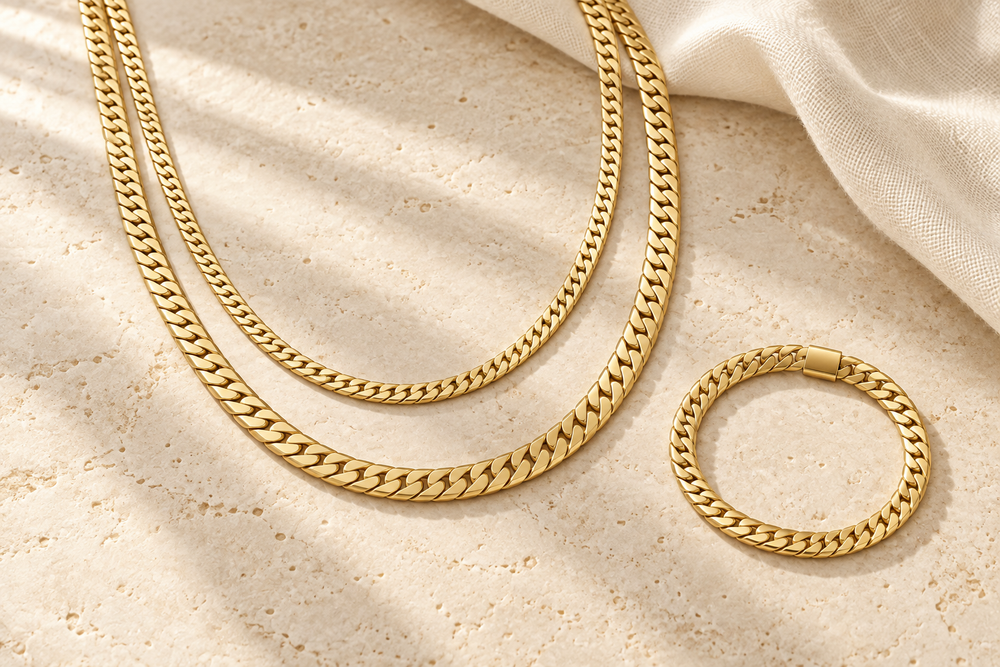 Gold chain layering editorial on warm ivory stone